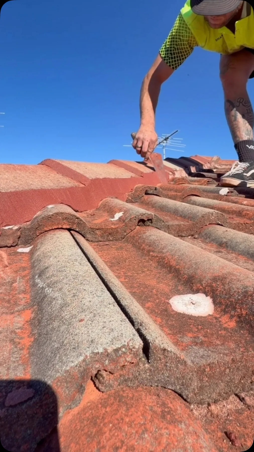 Roofer applying fresh pointing along terracotta ridge tiles